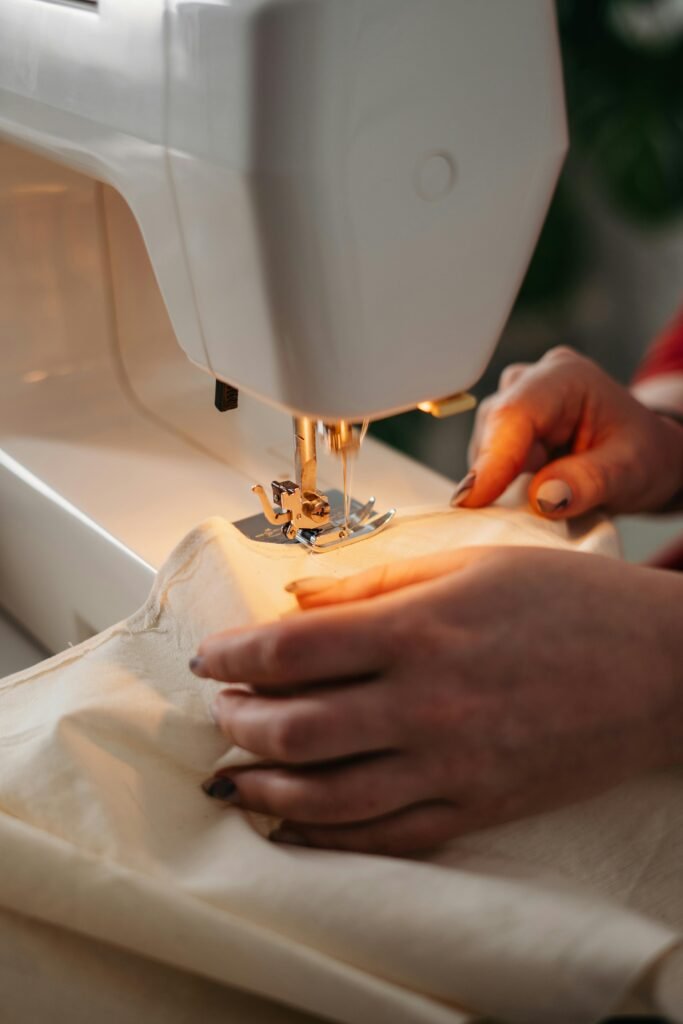pexels-photo-3738095-3738095-1 Detailed view of sewing process with hands guiding fabric on a machine.