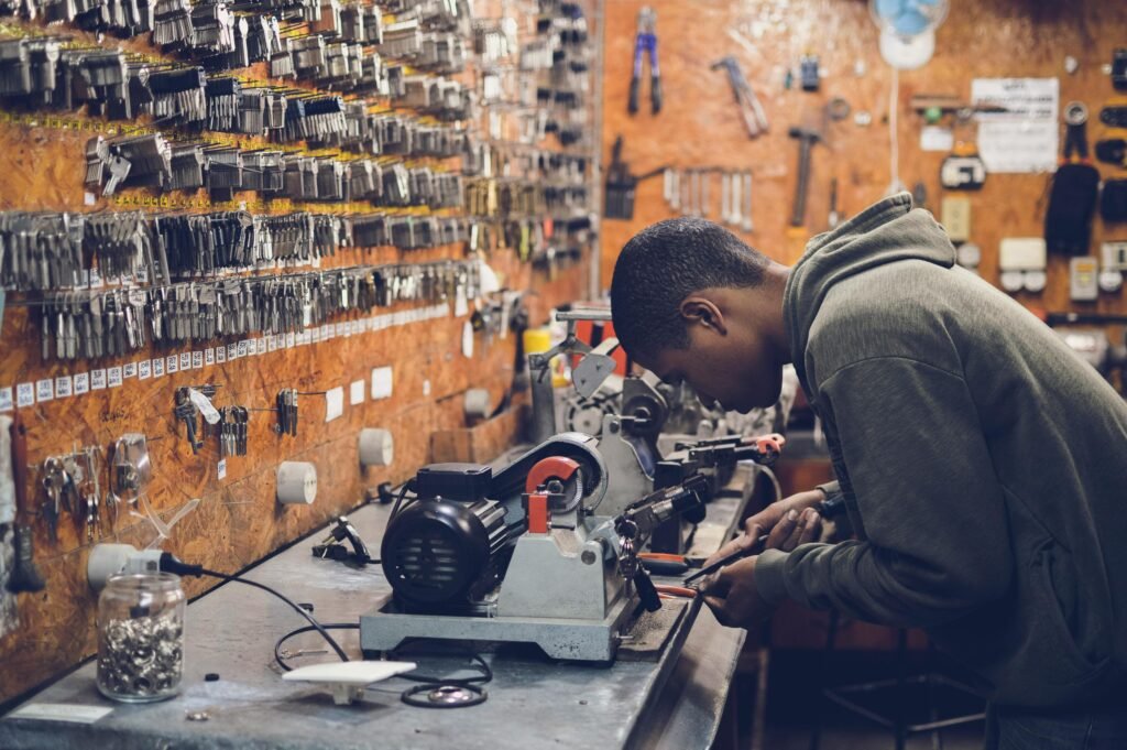 pexels-photo-64609-64609 A focused craftsman works in a key-making workshop surrounded by tools and equipment.